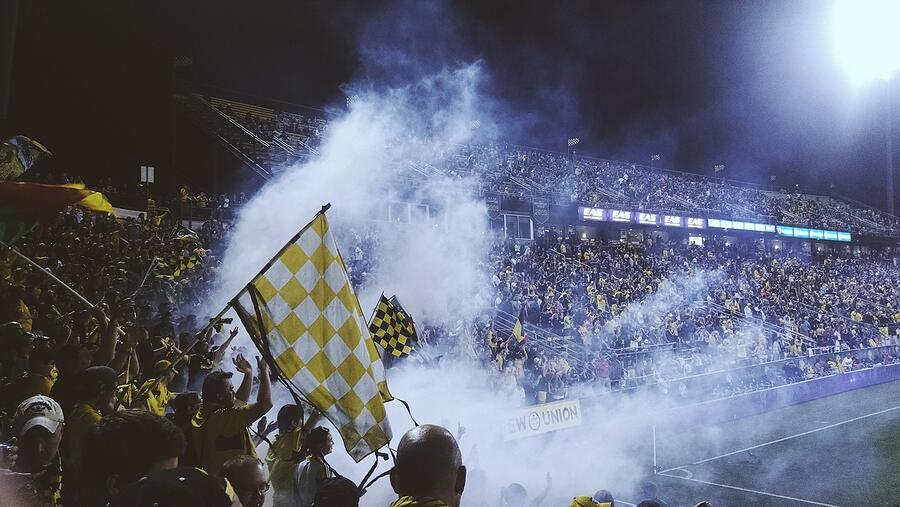 A stadium crowd with flags and smoke
